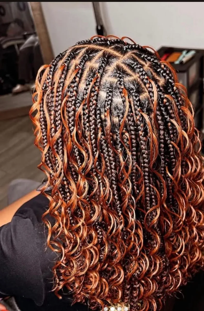 Shoulder-length bohemian knotless box braids with copper-highlighted curly loose ends over dark roots, neat square partings at the crown