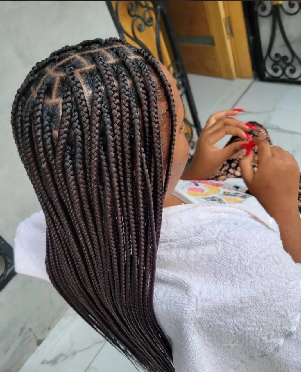 Small dark-brown knotless box braids with a clean triangle-part grid at the crown, shoulder length, viewed from above