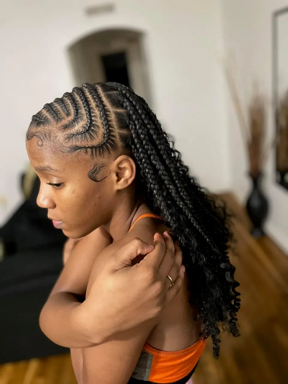 Jet-black side-swept lemonade feed-in braids flowing into loose curly ends, with sleek swirl-laid baby hair edges